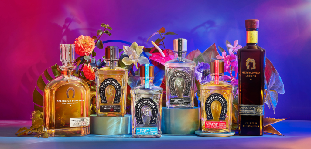 Many colorful bottles of Herradura Tequila on a tropical background